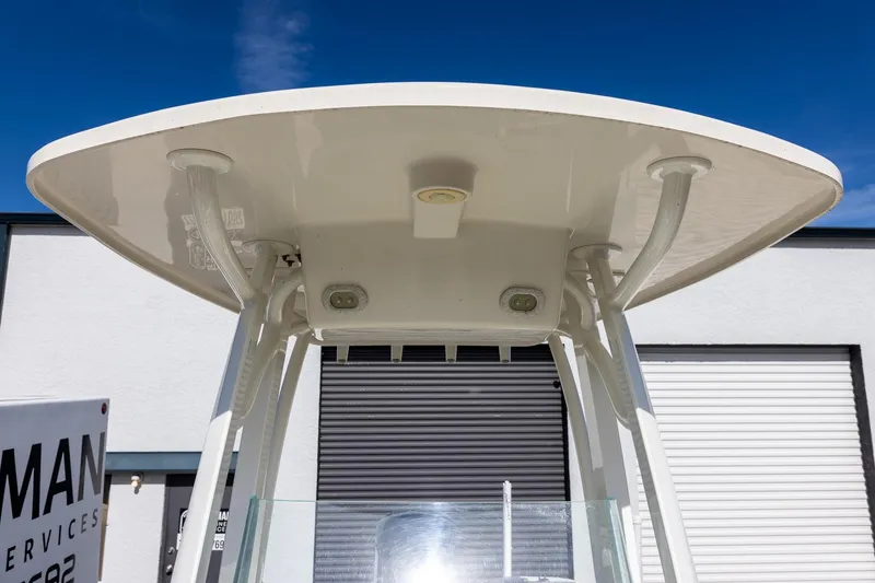 Slide: The Image of 2018 Sailfish 241 CC boat T-top against blue sky and building background. - 21