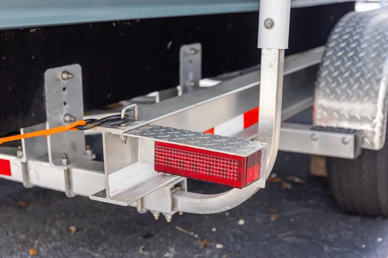 Slide: The Image of Trailer detail of a 2018 Sailfish 241 CC boat, featuring a red reflector and metal frame. - 31
