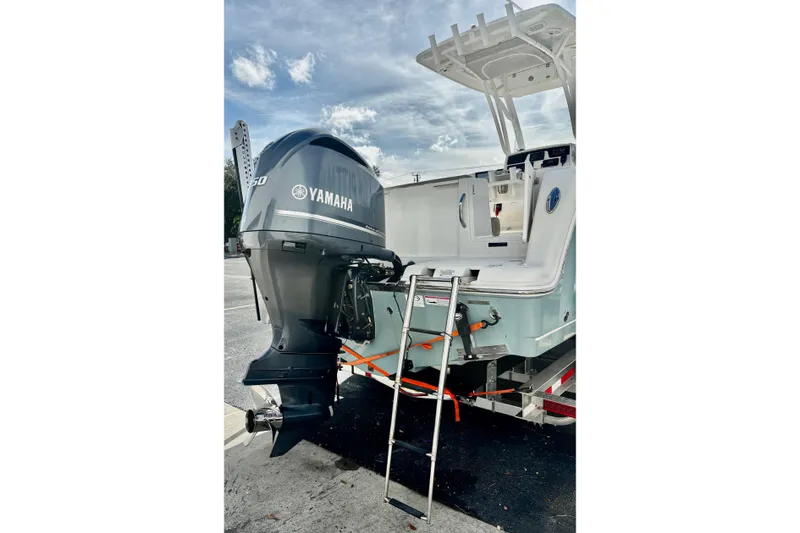 Slide: The Image of 2018 Sailfish 241 CC boat with Yamaha 150 engine and ladder, parked outdoors. - 4