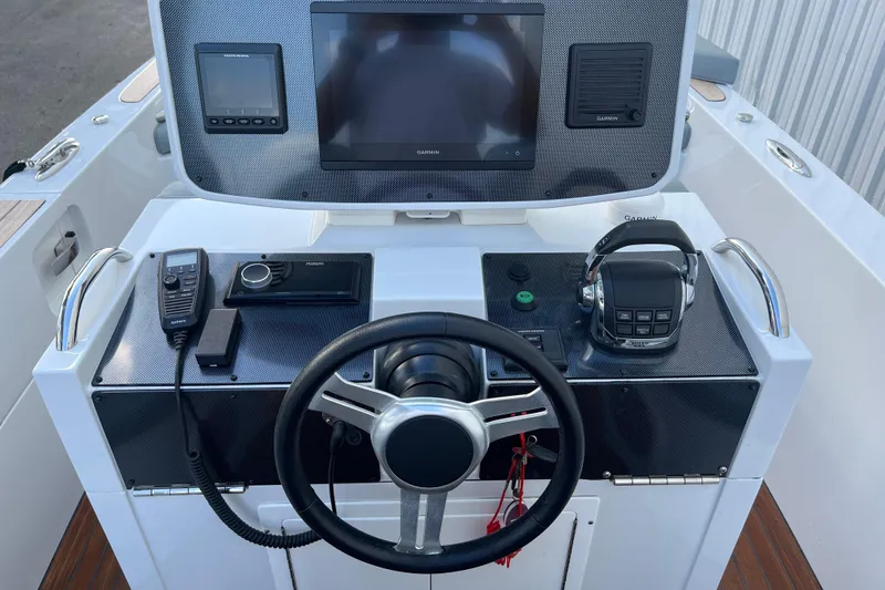Slide: The Image of Control panel of a 2021 Novurania Chase 19 boat with steering wheel and navigation equipment. - 1