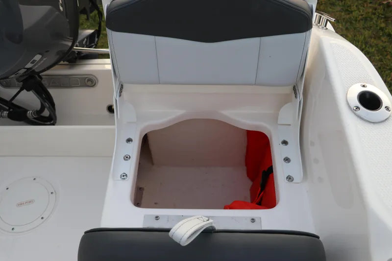 Slide: The Image of 2025 Robalo R160 Center Console boat seat storage compartment with visible life jacket. - 13