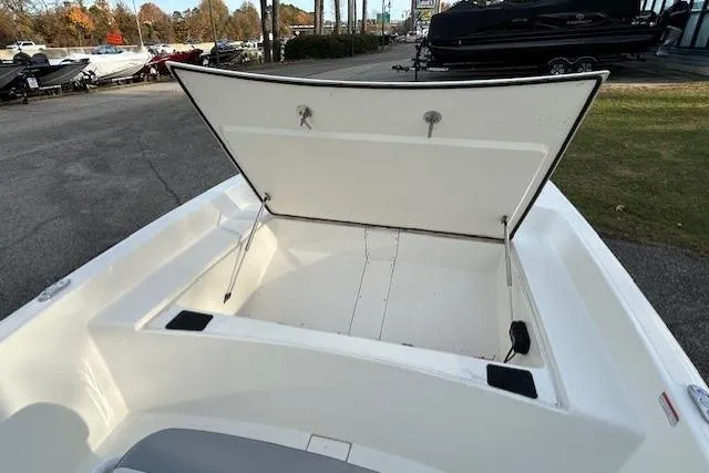 Slide: The Image of 2025 Mako Pro Skiff 17 CC boat with open storage compartment, parked outdoors. - 4