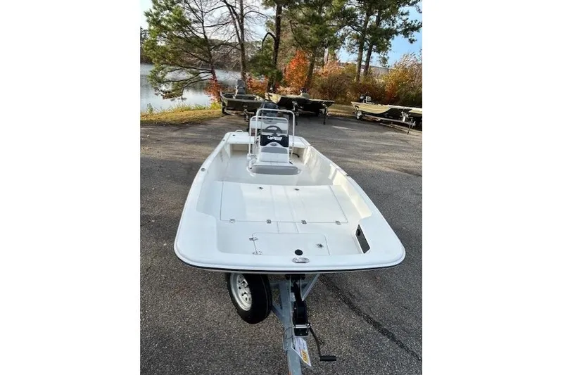 Slide: The Image of 2025 Mako Pro Skiff 17 CC boat on trailer, parked near a lake with autumn trees. - 7