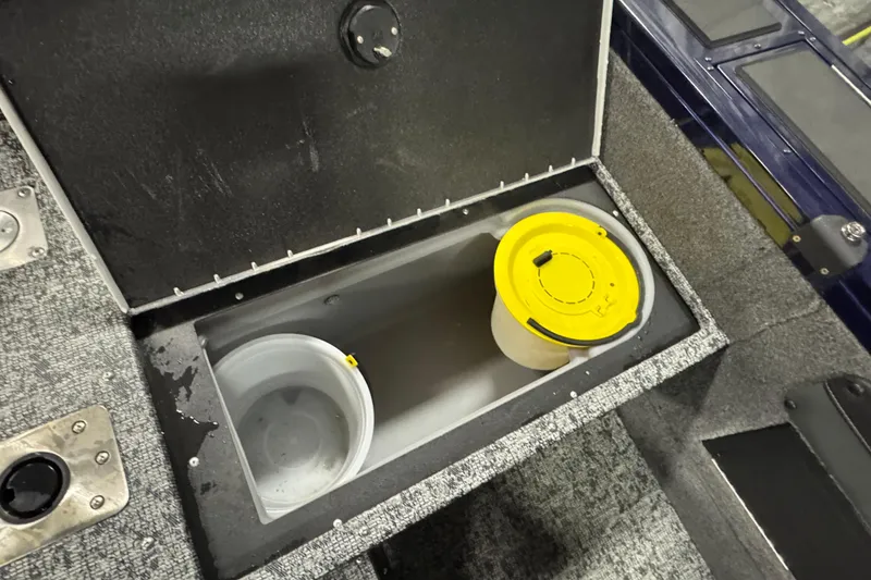 Slide: The Image of 2025 Tracker Targa V-19 WT storage compartment with containers, featuring a yellow lid. - 21