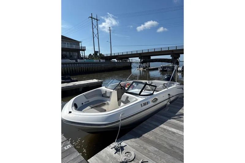 The Image of 2023 Bayliner VR6 Bowrider OB docked by a bridge on a sunny day. - 0