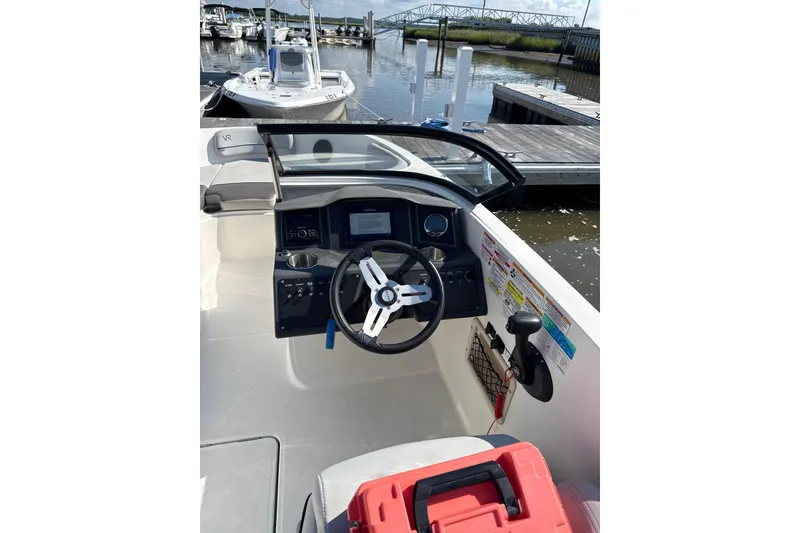Slide: The Image of 2023 Bayliner VR6 Bowrider OB cockpit with steering wheel and control panel at marina. - 3
