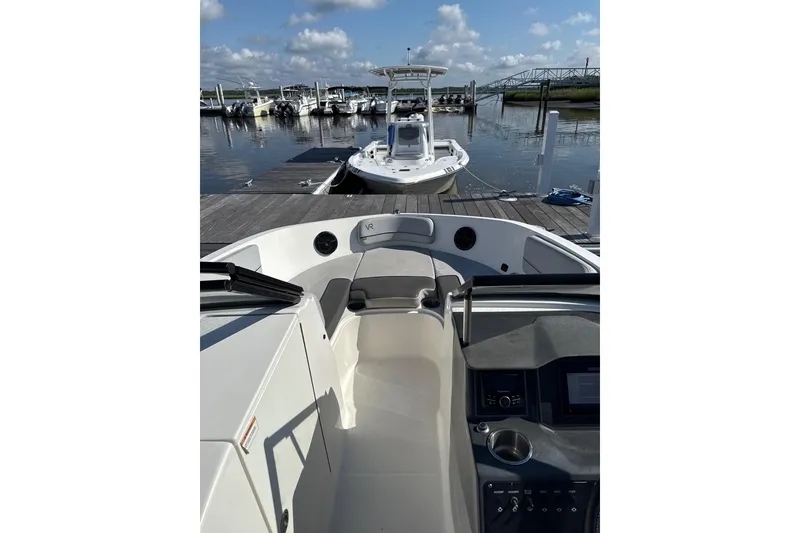 Slide: The Image of 2023 Bayliner VR6 Bowrider OB at marina, clear sky, docked boats in background. - 6