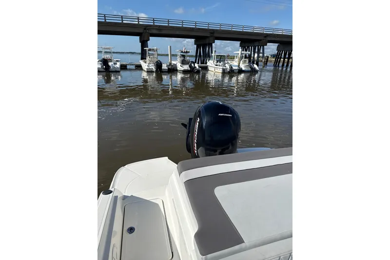 Slide: The Image of 2023 Bayliner VR6 Bowrider OB on water near docked boats and bridge. - 7