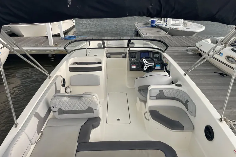 Slide: The Image of 2023 Bayliner VR6 Bowrider OB interior with seating and steering console at dock. - 7