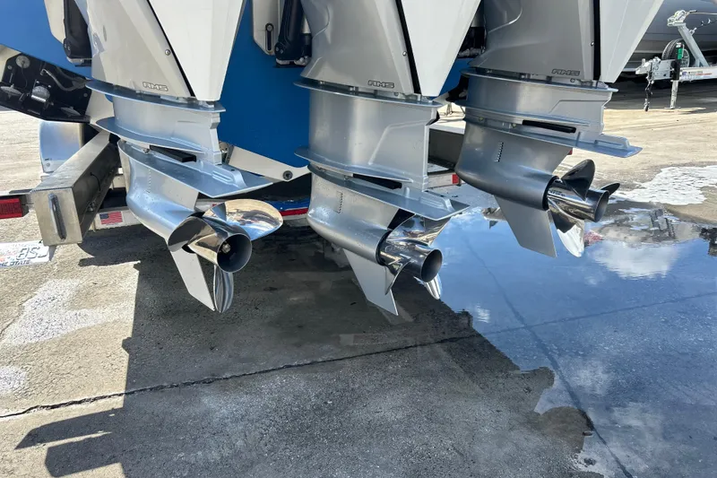 Slide: The Image of Triple outboard motors on a 2025 Contender 35 ST boat, reflecting on wet pavement. - 5
