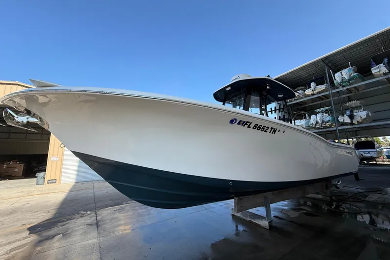 Slide: The Image of 2022 Tidewater 292 CC Adventure boat on calm water under clear blue sky. - 2