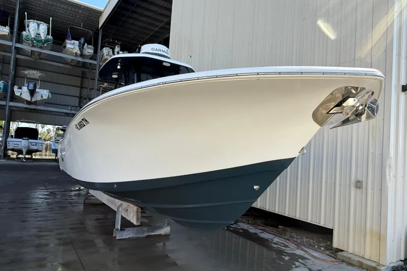 Slide: The Image of 2022 Tidewater 292 CC Adventure boat with dual engines in shallow water under clear sky. - 4