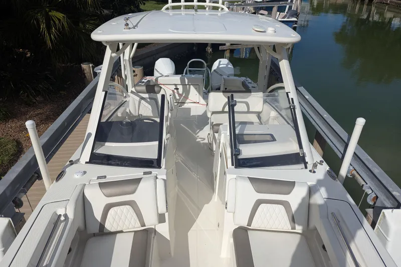 Slide: The Image of 2021 World Cat 280 DC-X boat interior, featuring seating and helm, docked by the water. - 10