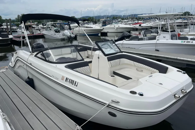 The Image of 2023 Bayliner DX 2200 boat docked at a marina, featuring sleek design and spacious seating. - 0
