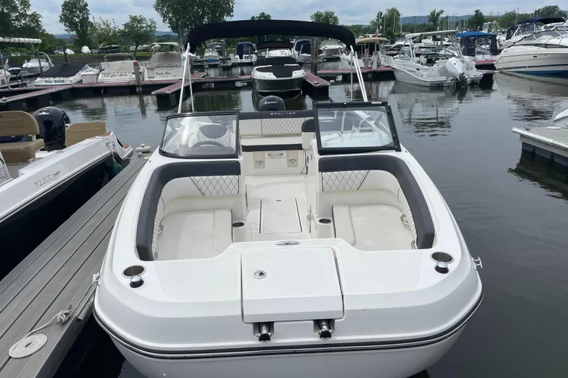 Slide: The Image of 2023 Bayliner DX 2200 boat docked at a marina, featuring spacious seating and sleek design. - 2