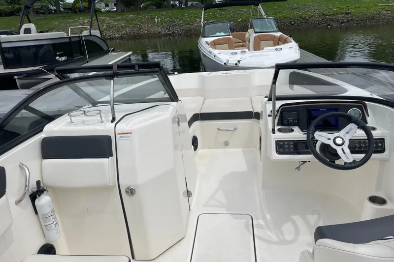 Slide: The Image of 2023 Bayliner DX 2200 boat interior with steering wheel and dashboard, docked by the water. - 3