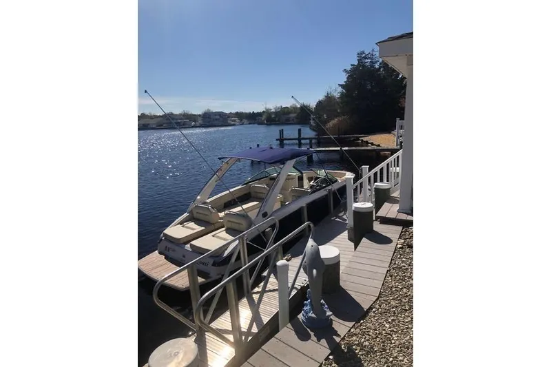 Slide: The Image of 2019 Regal LS6 boat docked by a sunny waterfront with a blue canopy. - 5