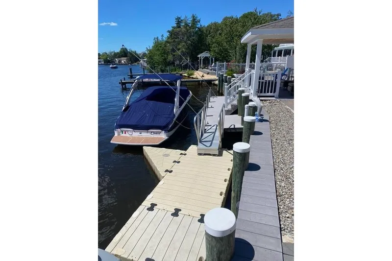 Slide: The Image of 2019 Regal LS6 boat docked at a lakeside pier on a sunny day. - 7