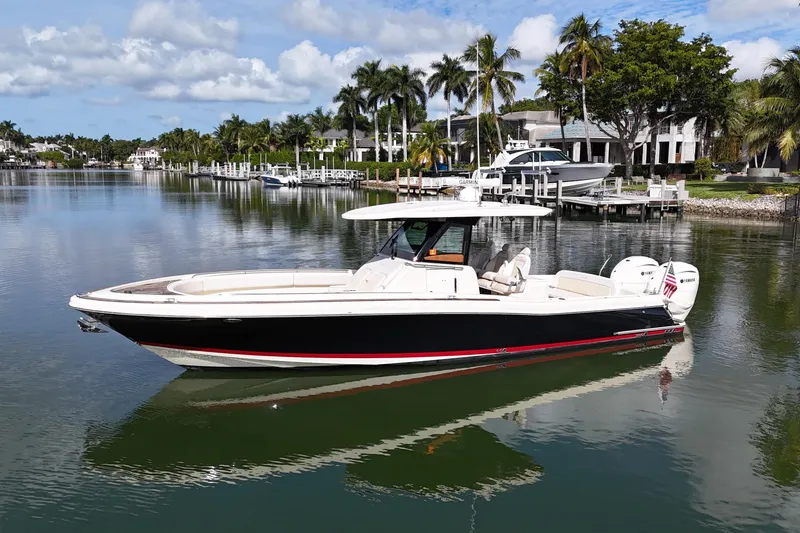 Slide: The Image of 2020 Chris-Craft Catalina 34 boat on calm water, surrounded by palm trees and luxury homes. - 6