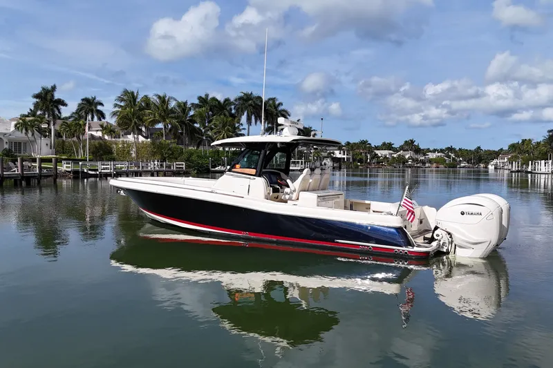 Slide: The Image of 2020 Chris-Craft Catalina 34 boat on calm water, surrounded by palm trees and luxury homes. - 8