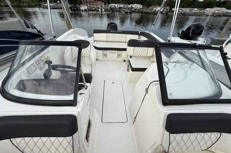 Slide: The Image of 2023 Bayliner DX 2200 boat interior with seating and steering wheel, docked by the water. - 3