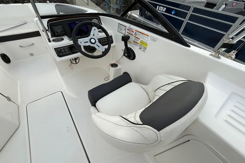 Slide: The Image of 2023 Bayliner DX 2200 boat cockpit with steering wheel and comfortable seating. - 6