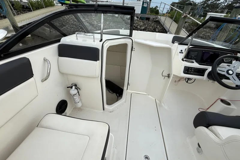 Slide: The Image of 2023 Bayliner DX 2200 boat interior with open cabin door and steering console. - 8