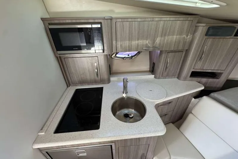 Slide: The Image of 2019 Regal 3350 Sport Cruiser kitchen with microwave, sink, and stove. - 12