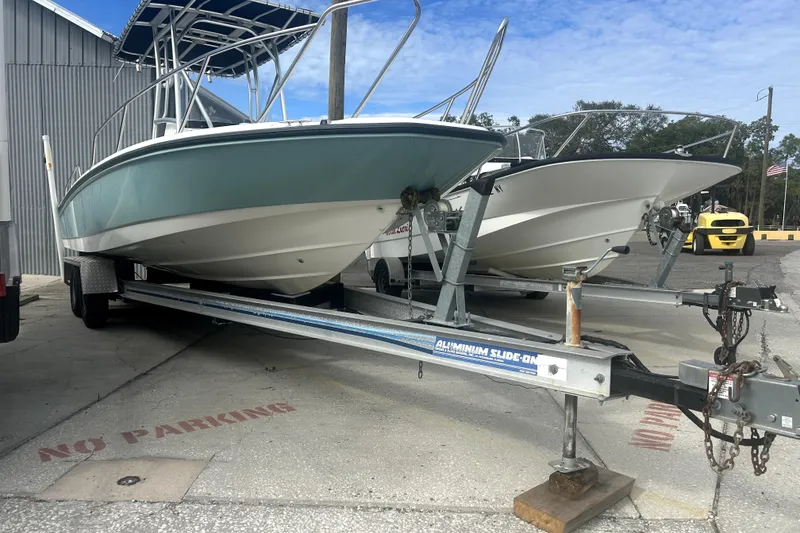 Slide: The Image of 2012 Boston Whaler 230 Dauntless boat on trailer, parked outdoors near a building. - 3