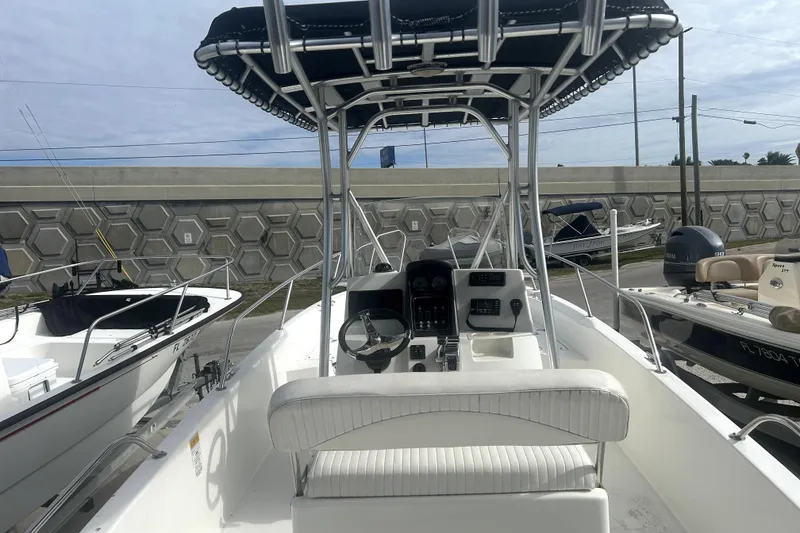 Slide: The Image of 2012 Boston Whaler 230 Dauntless boat with T-top and console, docked outdoors. - 9