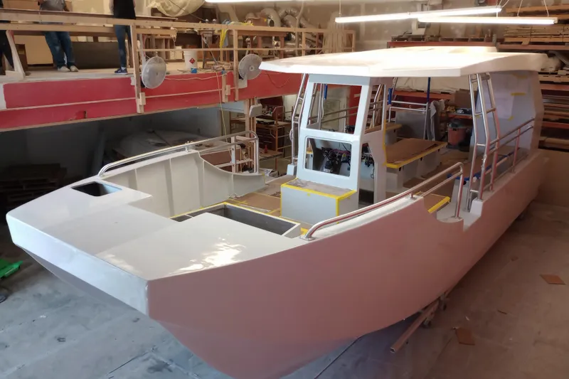 Slide: The Image of Custom Passenger Catamaran BYD34 2026 under construction in a workshop setting. - 7