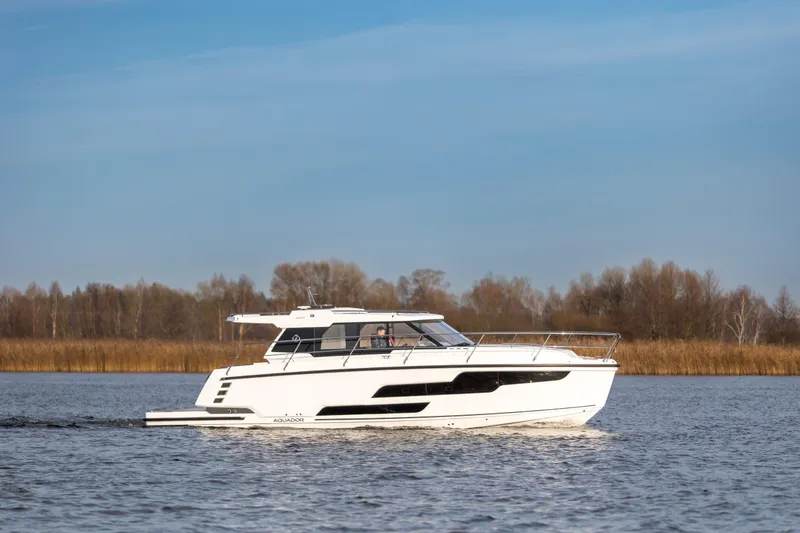 Slide: The Image of 2026 Aquador 400HT boat cruising on a calm lake with a scenic background. - 1