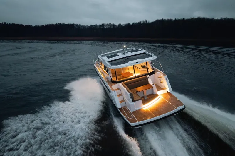 Slide: The Image of Aquador 400HT 2026 cruising on water at dusk with illuminated deck. - 21