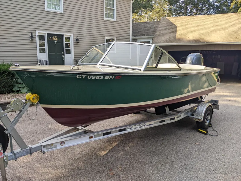 The Image of 2022 Rossiter 17 boat on trailer in driveway, green hull, parked near house. - 0