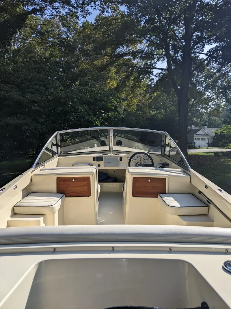 Slide: The Image of 2022 Rossiter 17 boat interior with seating, steering wheel, and dashboard, surrounded by trees. - 6