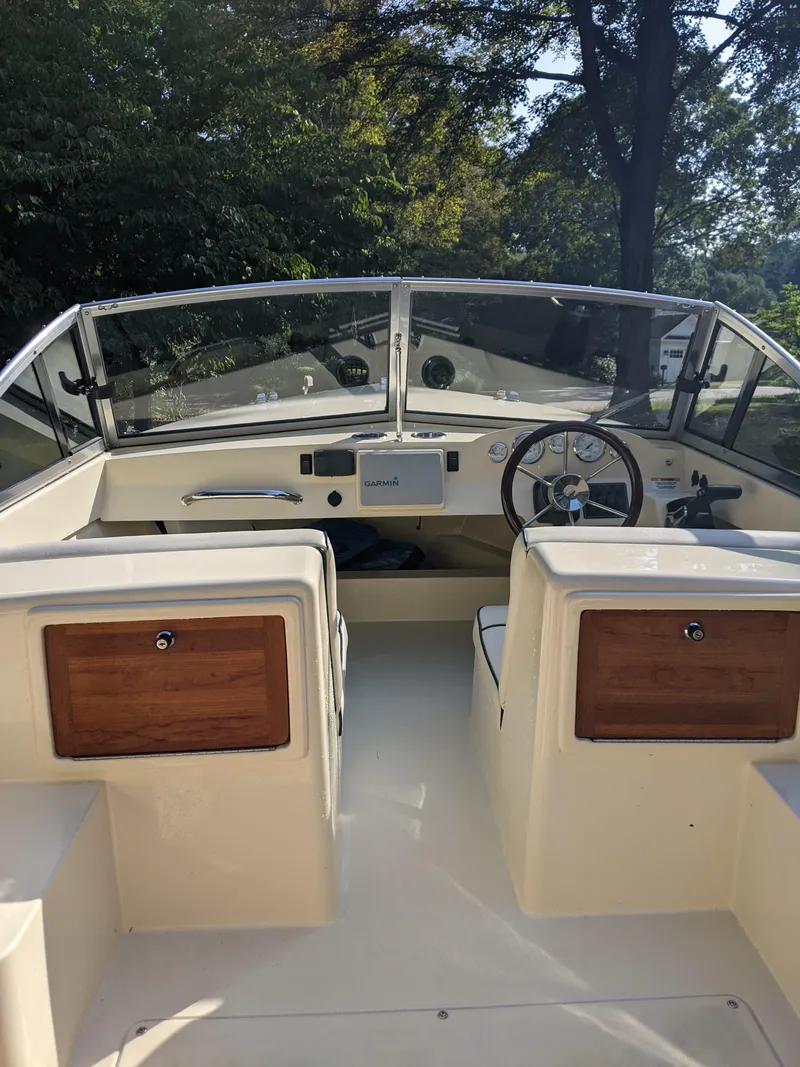 Slide: The Image of 2022 Rossiter 17 boat interior with steering wheel and wooden storage compartments. - 7