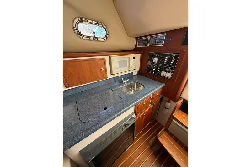Slide: The Image of 2005 Pursuit 3070 Offshore boat interior with kitchenette, sink, and control panel. - 12