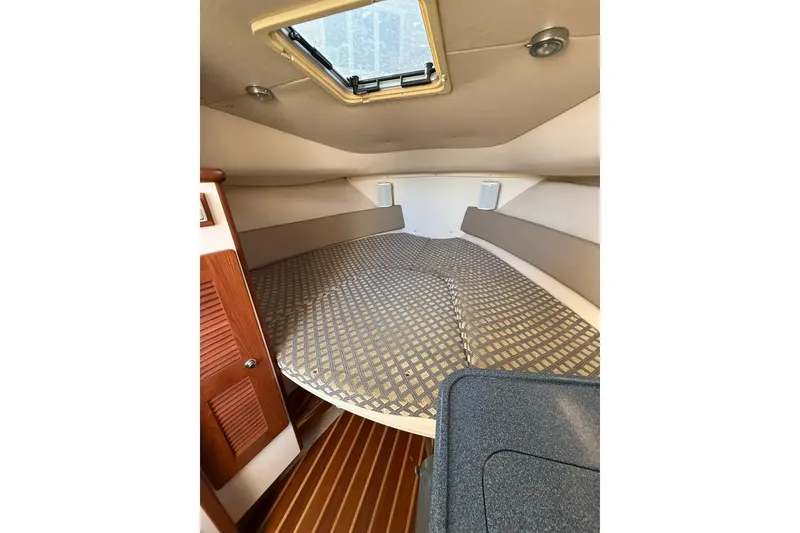Slide: The Image of 2005 Pursuit 3070 Offshore cabin interior with patterned bedding and wooden accents. - 13