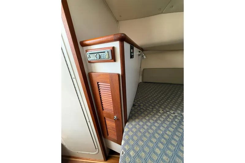 Slide: The Image of 2005 Pursuit 3070 Offshore cabin interior with wood paneling and patterned bedding. - 14