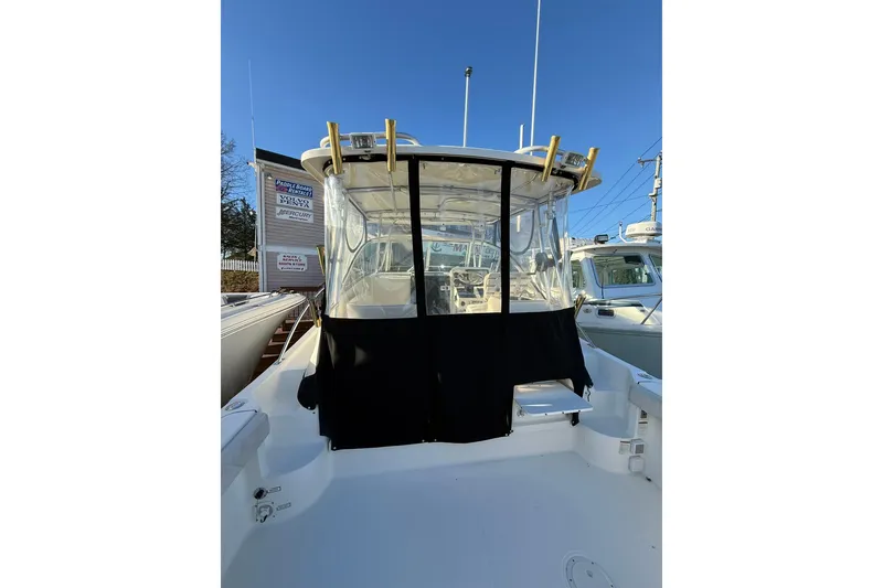 Slide: The Image of 2005 Pursuit 3070 Offshore boat with covered cockpit, docked under clear blue sky. - 6