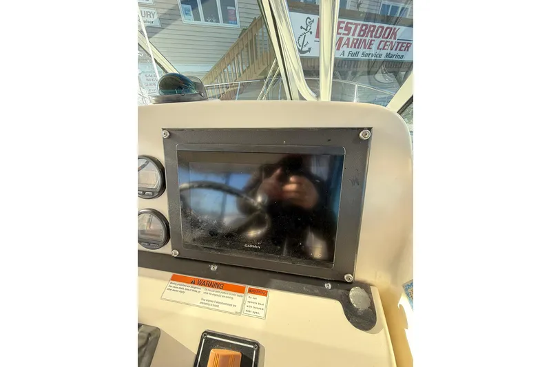 Slide: The Image of 2005 Pursuit 3070 Offshore boat dashboard with Garmin display and warning labels. - 9