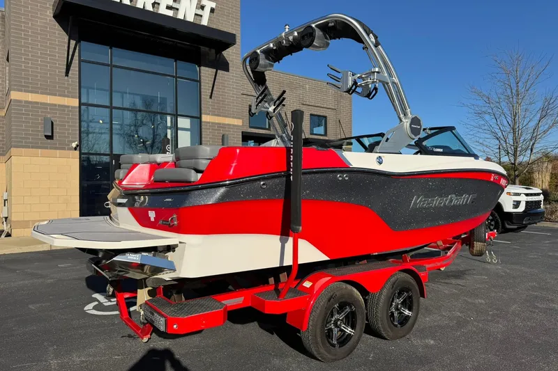 Slide: The Image of 2023 MasterCraft XT20 boat in vibrant red, parked on a trailer outside a building. - 3