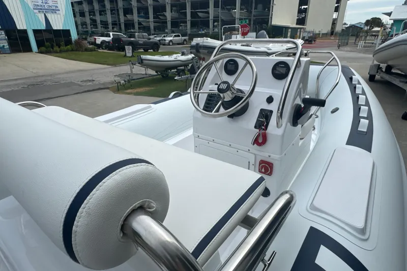 Slide: The Image of 2025 Novurania DL 460 boat interior with steering console and seating, docked at marina. - 7