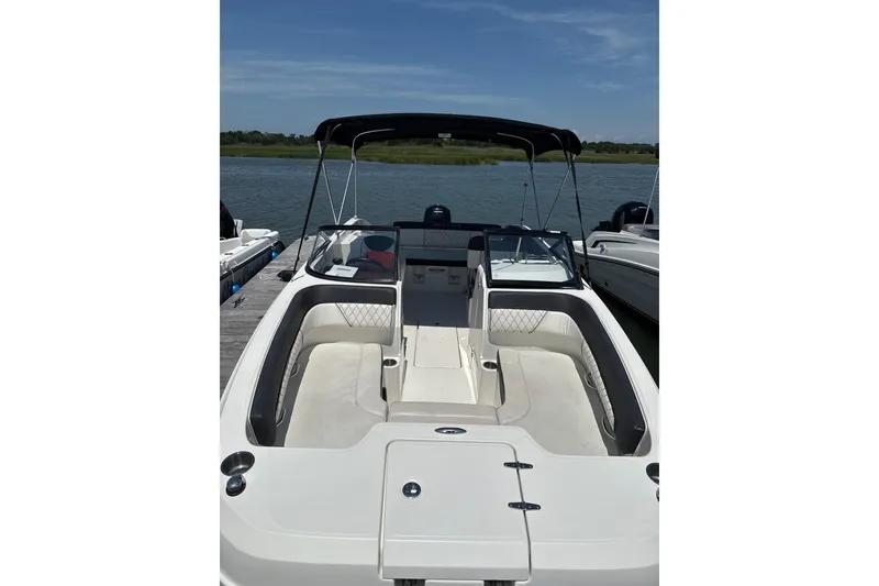 Slide: The Image of 2023 Bayliner DX 2200 boat with open seating, docked by a serene lake. - 3