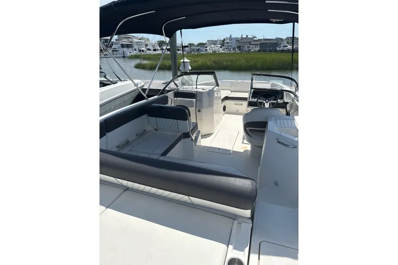 Slide: The Image of 2023 Bayliner DX 2200 boat interior with seating and steering wheel, docked near water. - 6