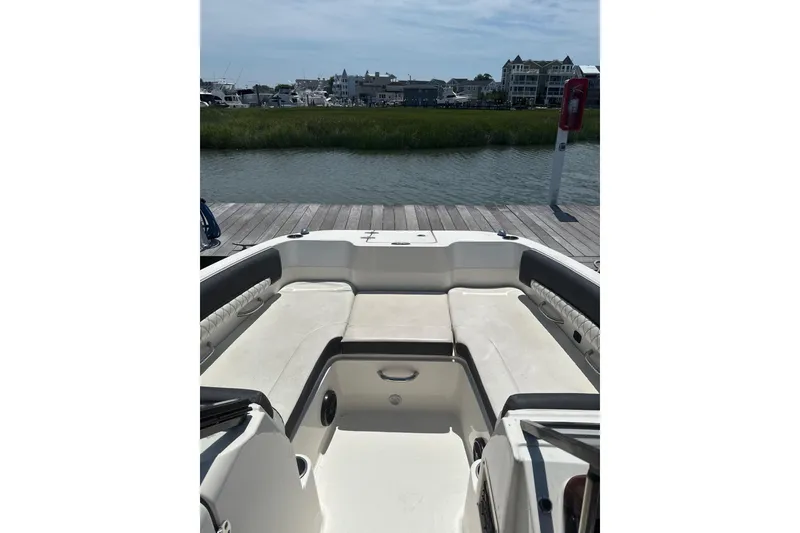 Slide: The Image of 2023 Bayliner DX 2200 boat interior with seating, docked by waterfront homes. - 8