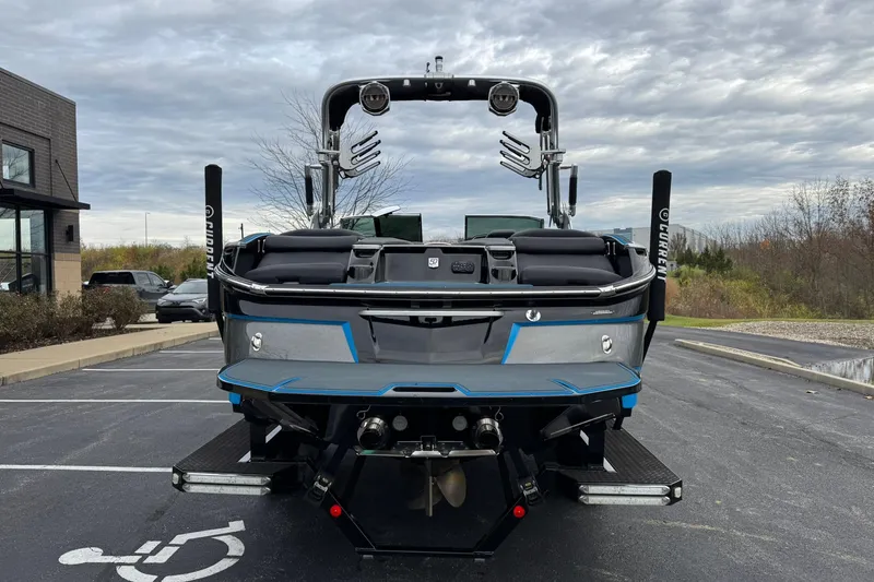 Slide: The Image of 2018 MasterCraft X23 boat parked in a lot, rear view, under cloudy sky. - 4