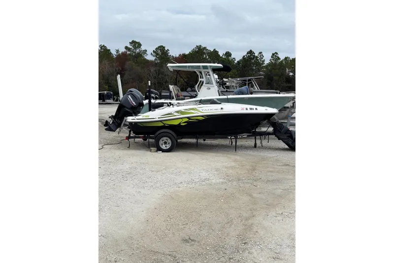 Slide: The Image of 2022 Tahoe T16 boat on trailer, parked outdoors with trees in background. - 11