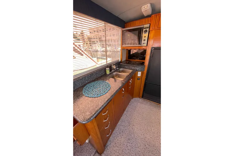 Slide: The Image of 1986 Ocean 38 Super Sport yacht kitchen with wooden cabinets and granite countertops. - 6