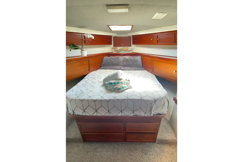 Slide: The Image of 1986 Ocean 38 Super Sport cabin with cozy bed, wooden cabinets, and natural light. - 8